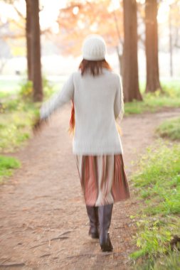 Genç ve güzel bir kadın sonbahar ormanında poz veriyor.