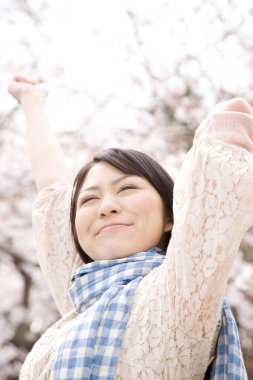 Sakura bahçesinde yürüyen güzel kadın, bulanık arka planda açık hava portresi. 