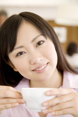 Kafede bir fincan çay içen genç Japon kadını yakından izleyin.