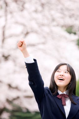 Çiçek açan kiraz ağacının arka planında okul üniformalı güzel Japon kızın portresi.