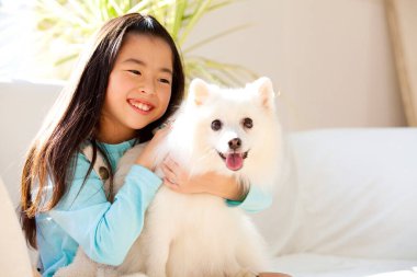 Şirin, mutlu Japon kızın yavru köpeğiyle portresi.