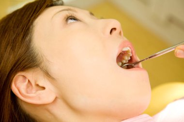 Genç bir kadın klinikte diş tedavisi görüyor.