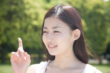 Güzel, gülümseyen genç bir Japon kadını parmağıyla dışarı işaret ediyor.
