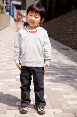 Dışarıdaki gülümseyen Asyalı küçük çocuğun uzun bir portresi.