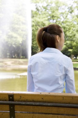 Asyalı kadın parkta dinleniyor, yaz günü.