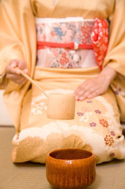 Geleneksel Japon çay töreninde kimono giyen ve matcha çayı hazırlayan bir kadın.   