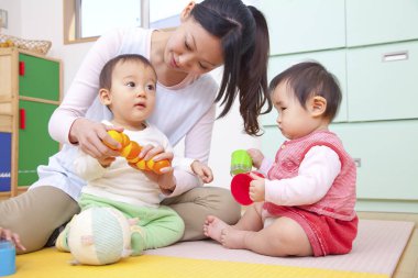 Küçük şirin Asyalı çocuklar Japon anaokulunda anneleriyle oynuyorlar.