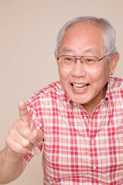 Gözlüklü Asyalı kıdemli adam el kol hareketi yapıyor ve konuşuyor.