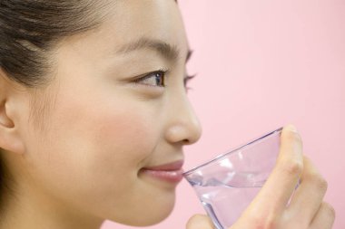 Kadın camdan su içiyor.