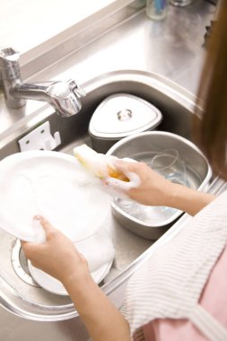 Kadınlar mutfak lavabosunda sofra takımlarını yıkıyor.