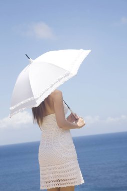 Yaz tatili boyunca deniz kenarında şemsiyesi olan bir kadının dikiz manzarası