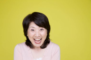 Sarı arka plandaki mutlu yaşlı kadın.