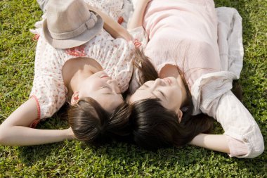 Japon kadınları gündüz vakti çayırda çimlerde yatıyorlar.  