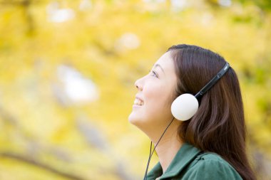 Park yerinde kulaklıklı genç Japon kadın.