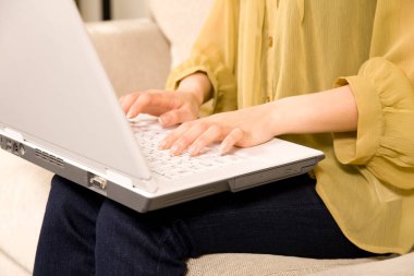 Güzel bir kadının evde dizüstü bilgisayar kullanırken çekilmiş görüntüsü.   