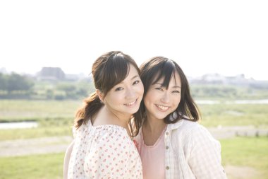 Güneşli bir günde gülümseyen iki Asyalı kız.