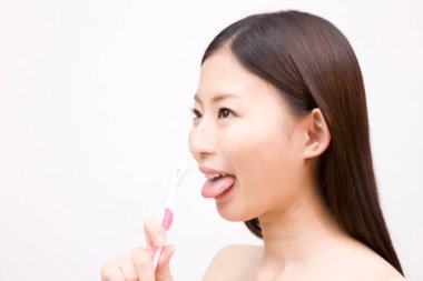 Hijyen için dil fırçası kullanan Asyalı kadın.