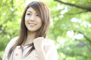 Güzel genç Asyalı kadın gülümsüyor ve dışarı bakıyor.  