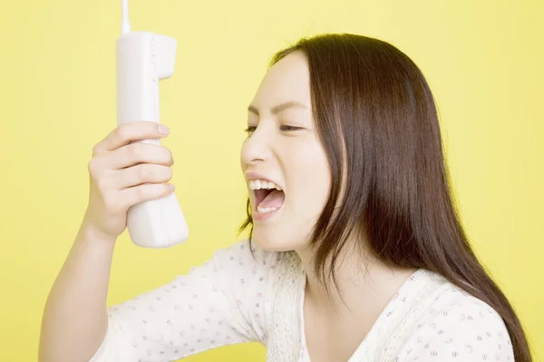 黄色の背景に隔離された電話で叫ぶ美しい日本の女性の肖像画 — ストック写真
