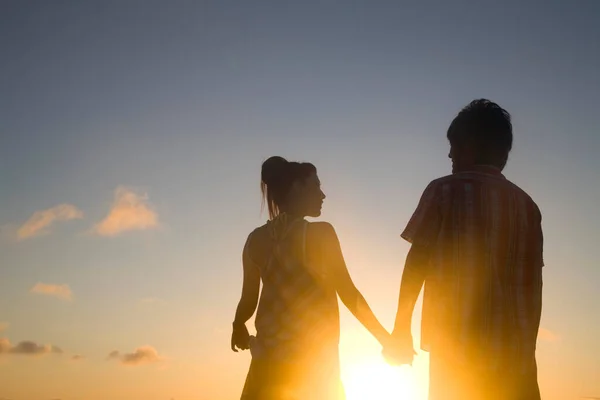 日没にビーチで手を握っている幸せなカップルのシルエット — ストック写真