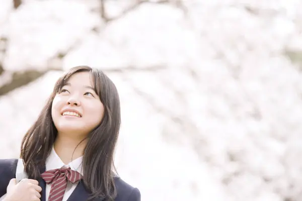 美丽的身着校服的日本女孩的肖像 背景是盛开的樱桃树 — 图库照片