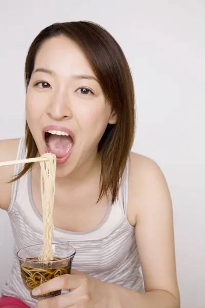 年轻的亚洲女人用筷子吃面条 — 图库照片