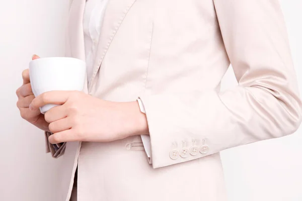 灰色の背景に白いコップを保持している若いビジネスマンのクロップショット — ストック写真