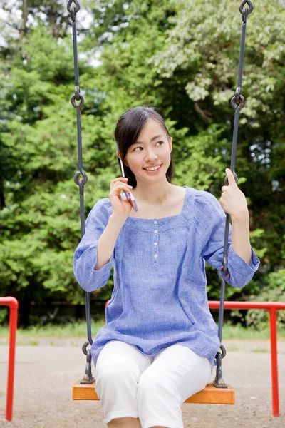 Glada Japanska Kvinna Sitter Swing Använda Telefon Grön Sommarpark Dagtid — Stockfoto