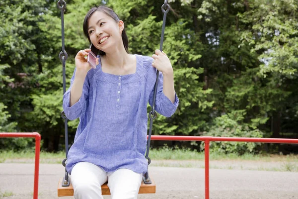 Allegra Donna Giapponese Seduta Sull Altalena Usare Telefono Nel Parco — Foto Stock
