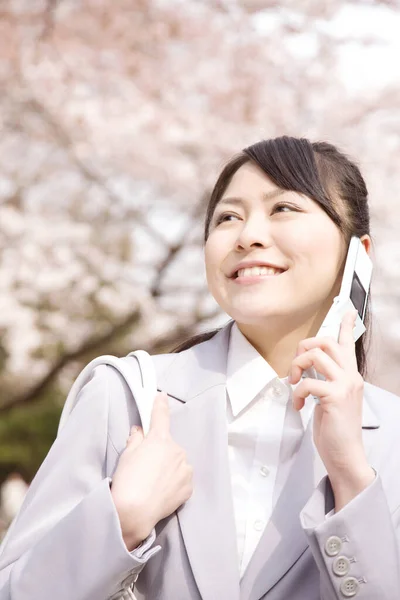 美丽微笑的年轻女商人春天在公园里用手机的肖像 — 图库照片