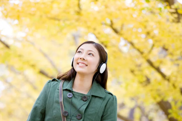 Junge Japanerin Mit Kopfhörern Park lizenzfreie Stockbilder