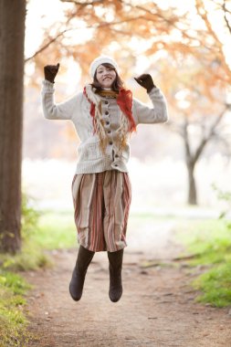 Genç ve güzel bir kadın sonbahar ormanında poz veriyor.