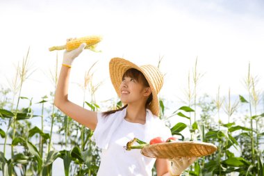 Tarlada bir sepet sebzeli mutlu genç kadın.