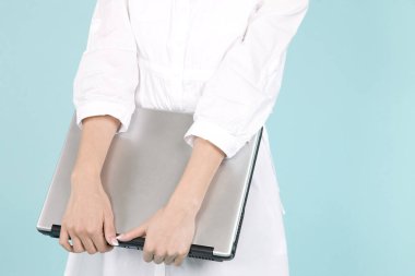 Dizüstü bilgisayarı olan güzel genç bir kadın mavi arka planda izole edilmiş.