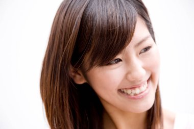 Beyaz arka planda gülümseyen Asyalı genç kadının portresi