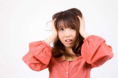 Hayal kırıklığına uğramış genç Japon kadın portresi. Beyaz arka planda, elleri başının üstünde poz veriyor.