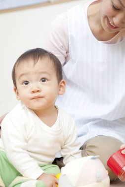 Küçük tatlı çocuk Japon anaokulunda öğretmenle oynuyor.