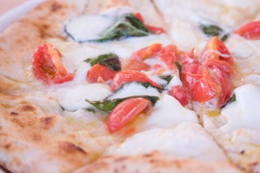 Mozzarella peyniri, fesleğen ve parmak uçlarıyla taze pizza.