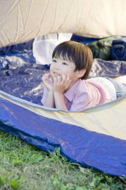 Asyalı küçük çocuk kamp çadırında poz veriyor.