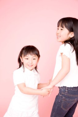 İki küçük Asyalı kız el ele tutuşuyorlar. 