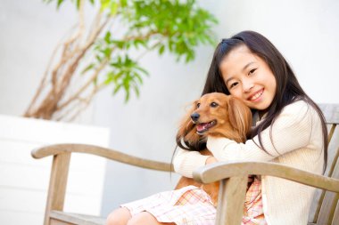 Şirin, mutlu Japon kızın yavru köpeğiyle portresi.