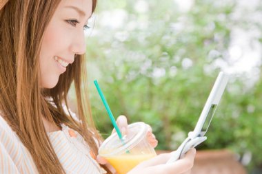 Güzel genç Asyalı kadın kokteyl içiyor ve dışarıda telefon kullanıyor.   