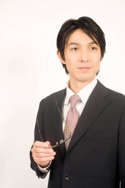 Elinde gözlüklerle yakışıklı Asyalı iş adamının portresi 