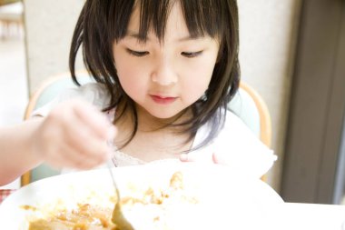 Küçük Asyalı kız Japon yemeği yiyor. 