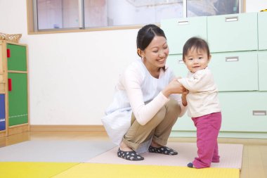 Küçük tatlı çocuk Japon anaokulunda öğretmenle oynuyor.