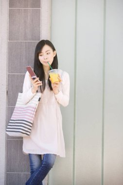 Japon bayan açık havada telefon kullanıyor, gündüz görüşü var.