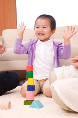 Asyalı aile büyükbaba ve büyükanne torunlarıyla yerde tahta küplerle oynuyorlar.