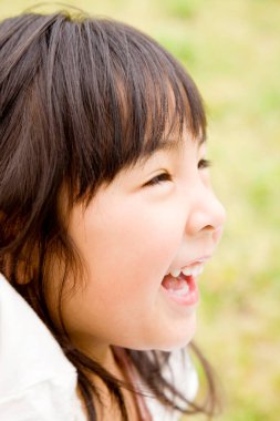 Yaz parkında gülümseyen küçük Asyalı kız.