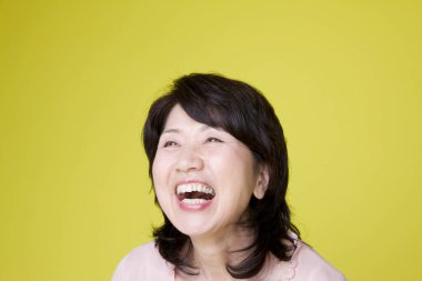 Sarı arka plandaki mutlu yaşlı kadın.