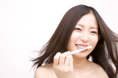 Asyalı kadın diş fırçasıyla dişlerini fırçalıyor